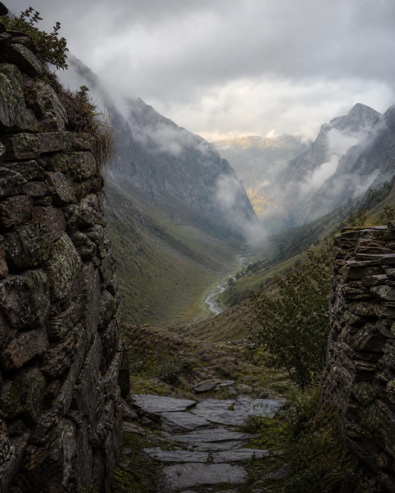 Weathered stone passage opening onto a mist-covered mountain valley